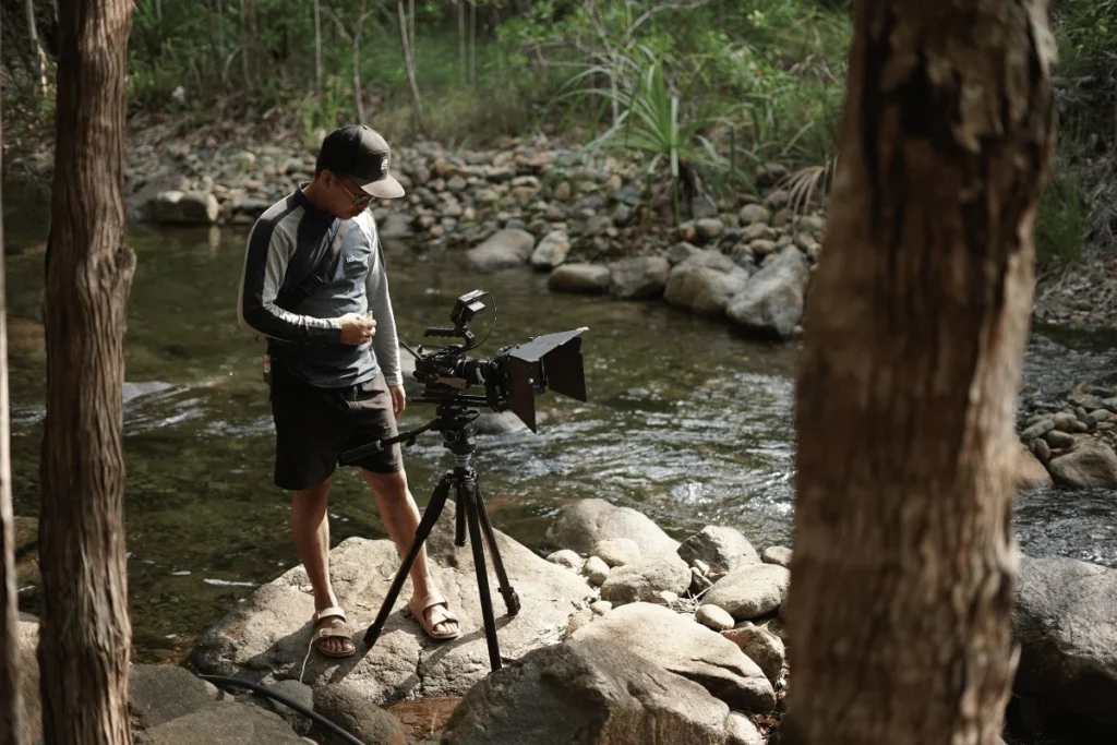 Eco-Friendly Filmmaking in Fragile Himalayan Ecosystems Eco-friendly filmmaking with a professional camera setup beside a natural river, showcasing sustainable film production practices in an outdoor environment.