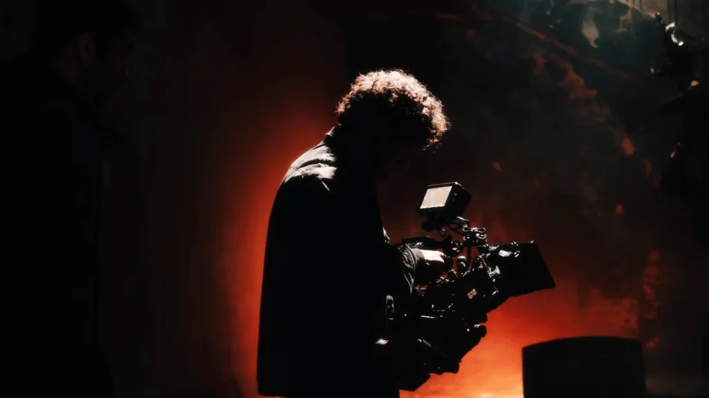 Film Production Security in Nepal: Protecting Cast, Crew, and Equipment On Set On-set film security in Nepal: crew member framing a shot with professional camera rig amid fire-lit atmosphere