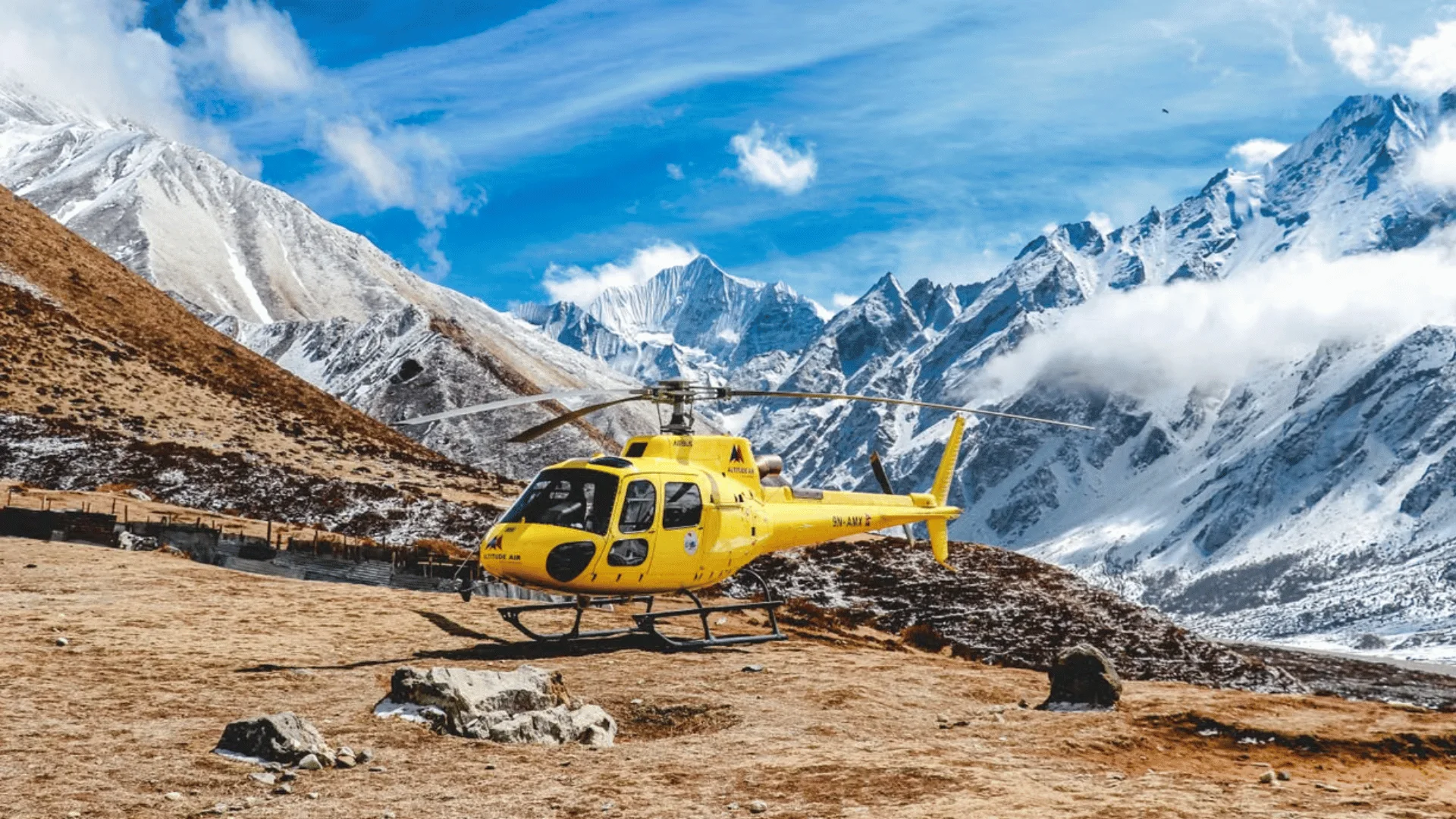 Film crew safety in Nepal, with a yellow helicopter parked in the snow-covered Himalayas for emergency medical evacuation in remote, high-altitude locations.